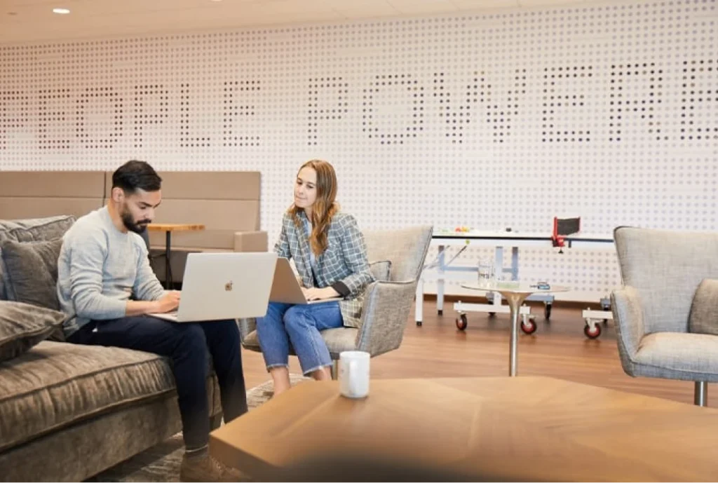Photo of teammates working together on laptops in front of a wall that reads "People Power"